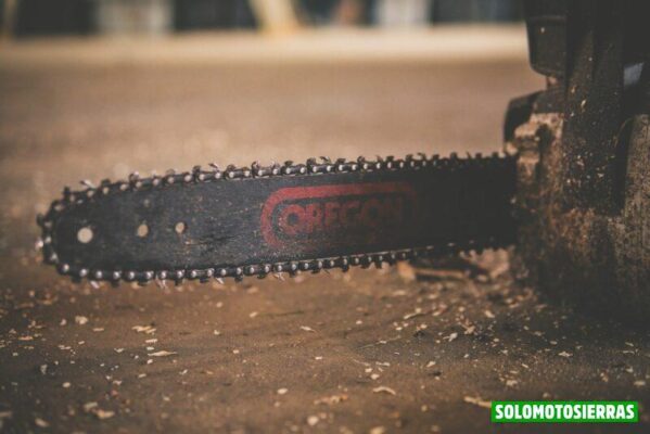 black and red Oregon chainsaw on brown wood plank